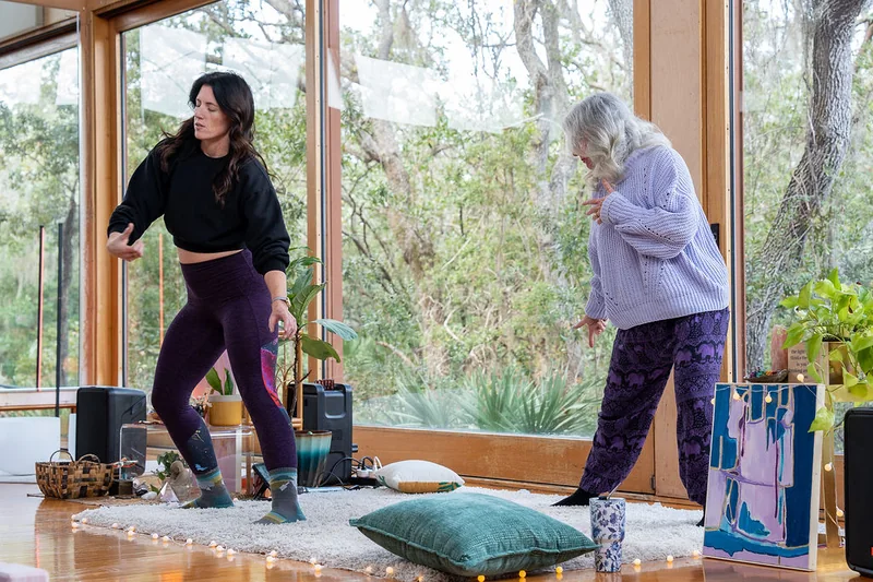 Sarah and Petey dancing together in front of the studio windows