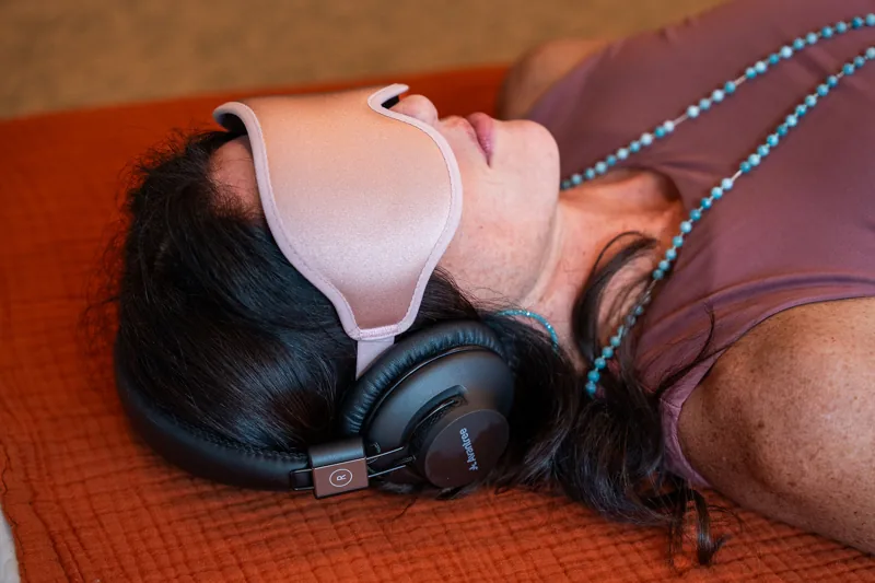 Sarah in a journey wearing an eye mask and headphones
