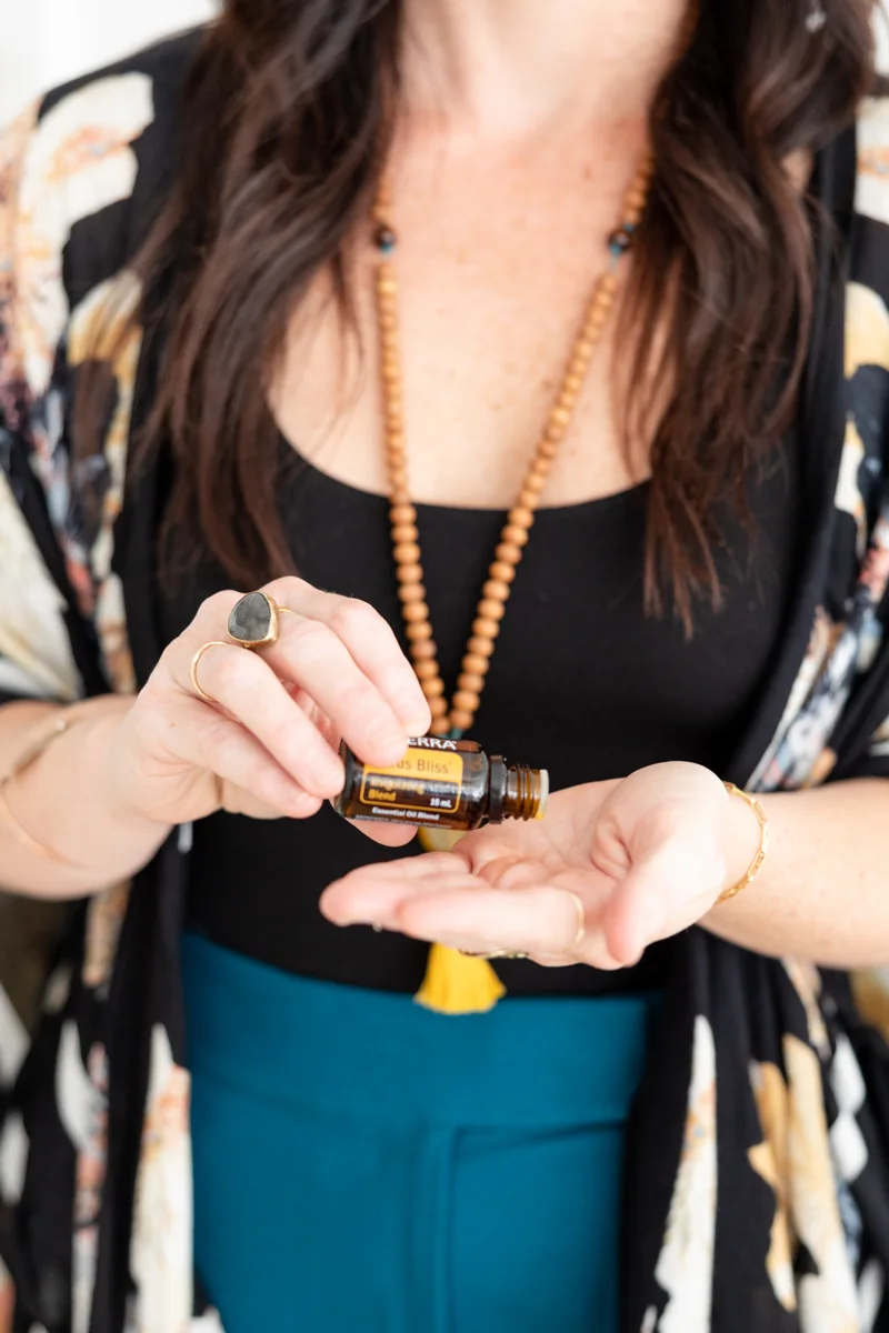 Sarah’s hands holding a bottle of essential oil as she prepares