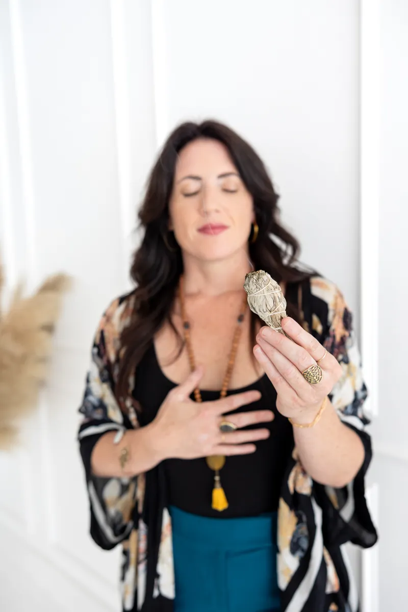Sarah in prayer with sage, eyes closed